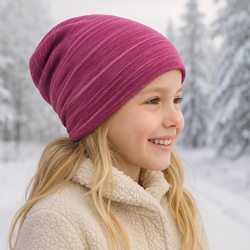 Mädchen trägt Wollhuhn Öko Long Beanie in Schnee; zweilagig, weicher Baumwolljersey, wendbar, ideal für kaltes Wetter und ganzjährig tragbar.
