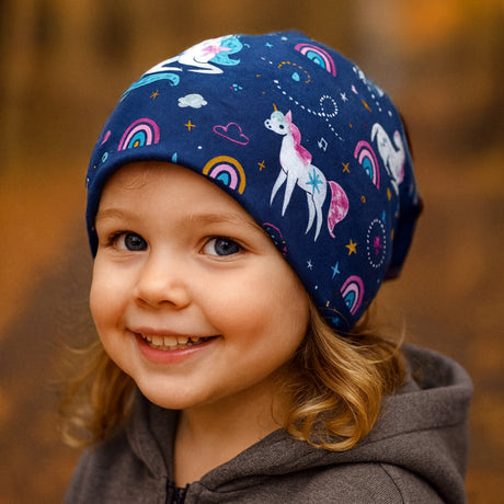 Kind trägt Wollhuhn Öko Long Beanie, zweilagig, dunkelblau mit Einhornmuster. Beanie sitzt lässig und bietet Komfort und Wärme. Ideal für Herbsttage.