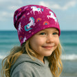 Wollhuhn Öko Long Beanie, zweilagige Wendemütze, lässiger Schnitt, handgemacht aus weichem Öko-Jersey, ideal für Kinder, mit Einhorn-Motiv auf pinkem Hintergrund.