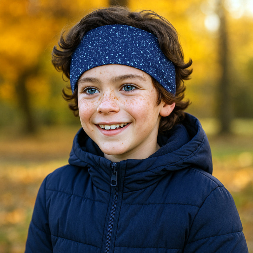 Junger Junge trägt ein Wollhuhn Elastisches Öko Stirnband/Haarband Jersey Zweilagig Breit Galaxy Sprenkel Blau, passend zur kühlen Herbstumgebung.