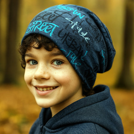 Junger Junge im Herbstwald trägt eine Wollhuhn Öko Long Beanie, eine zweilagige, handgemachte Wendemütze in Blau, zeigt ein lässiges, bequemes Design.