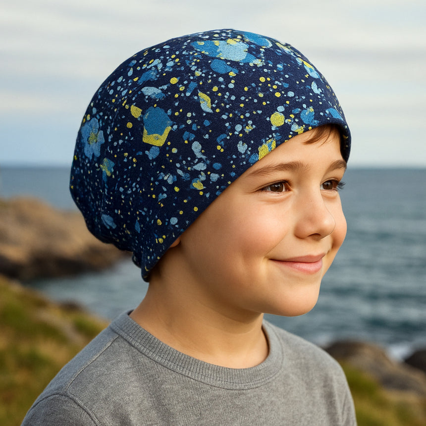 Junge trägt die Wollhuhn Öko Long Beanie, zweilagig und wendbar, in Dunkelblau. Ideal für jede Jahreszeit, bequem und aus weichem Öko-Jersey gefertigt.