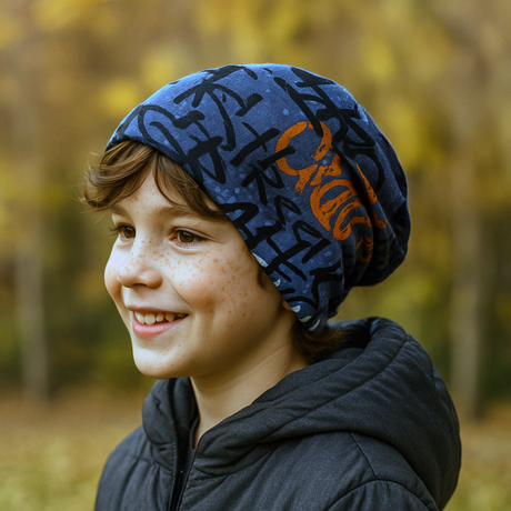 Junge trägt Wollhuhn Öko Long Beanie, zweilagig und wendbar in Grau/Orange, ideal für ganzjähriges Tragen, bequem und formbeständig in herbstlicher Umgebung.