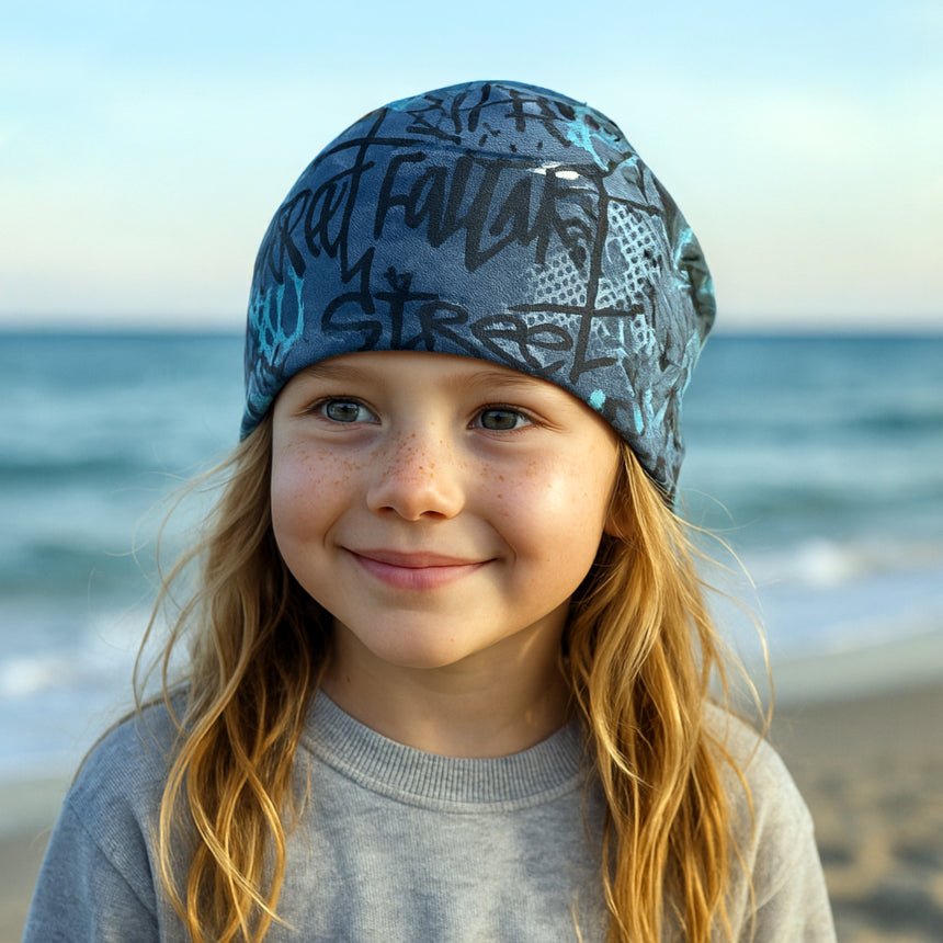 Mädchen trägt Wollhuhn Öko Shorties Wendemütze, zweilagig, ideal für aktive Kinder. Lässiger Stil, handgemacht, bequem und mitwachsend. Perfekt für Schule und Freizeit.