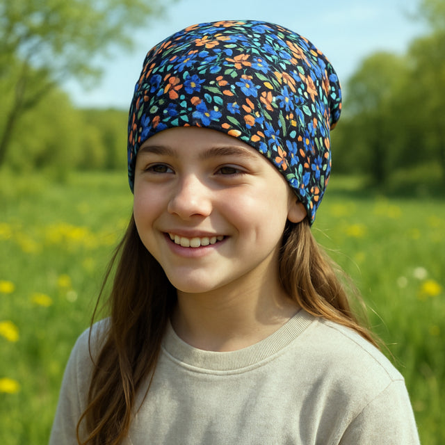 Mädchen trägt Wollhuhn Öko Shorties, zweilagige Wendemütze, stilvoll in Blumen Schwarz/Bunt, perfekt für aktive Kinder, handgefertigt in Deutschland.