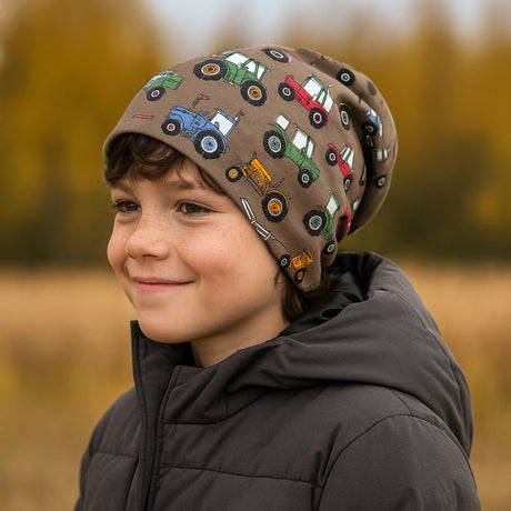 Kind trägt Wollhuhn Öko Long Beanie, zweilagig, mit Traktor-Muster in Braun, lässiger Stil, perfekt für jede Jahreszeit, hält warm und bequem.