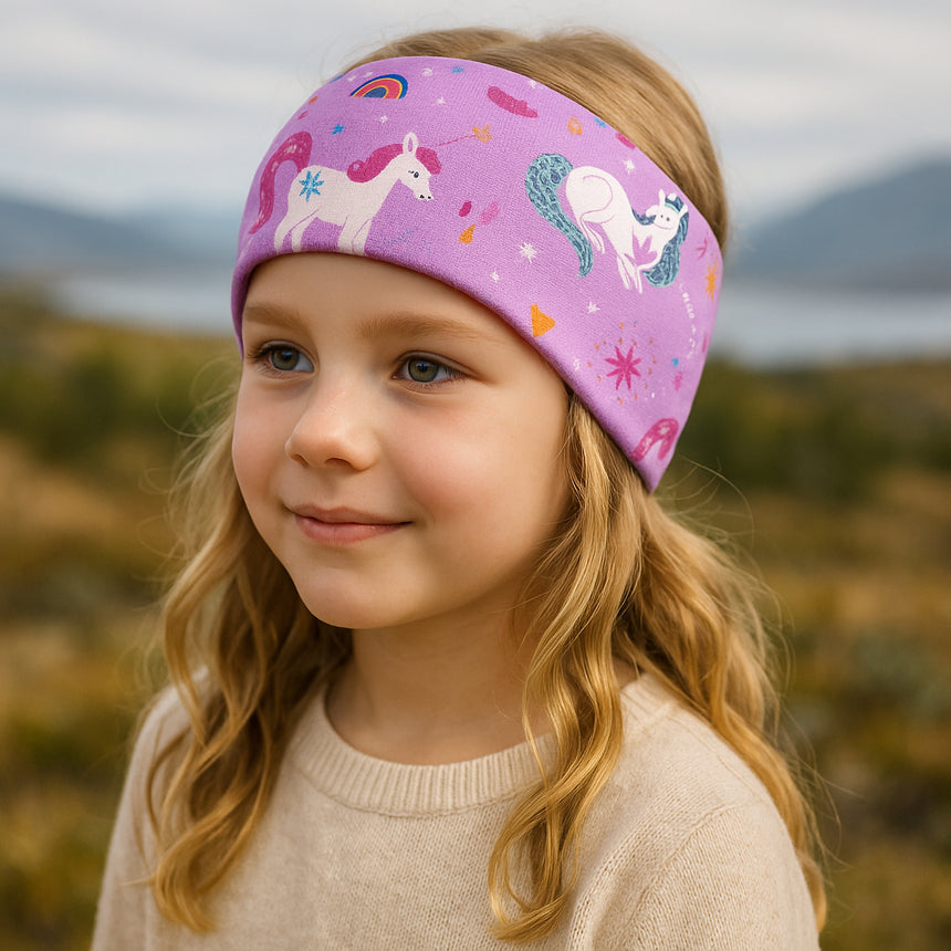 Mädchen trägt ein Wollhuhn Elastisches Öko Stirnband mit Einhornmotiv, ideal für Sport und Freizeit, aus weichem Bio-Jersey, handgemacht in Deutschland.