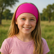 Mädchen trägt Wollhuhn Elastisches Öko Stirnband, zweilagig, breit, in Pink. Handgemacht in Deutschland, ideal für Sport und Outdoor-Aktivitäten.