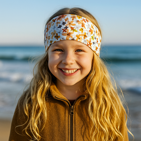 Mädchen am Strand trägt Wollhuhn Elastisches Öko Stirnband, Jersey, zweilagig, breit, mit Aquarellblumenmuster, ideal für Alltag und Outdoor-Aktivitäten.