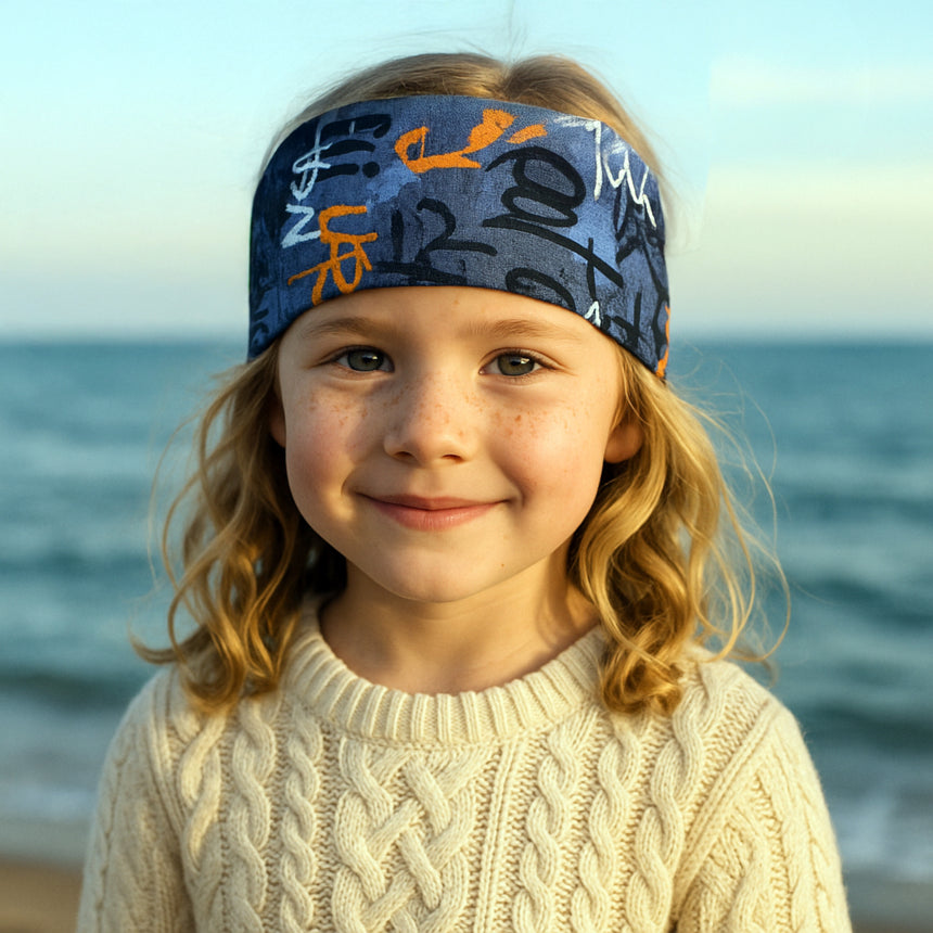 Mädchen trägt Wollhuhn Elastisches Öko Stirnband, Jersey, zweilagig, breit, ideal für Aktivitäten und Helme, handgemacht in Deutschland. Perfekter Sitz, weich und dehnbar.