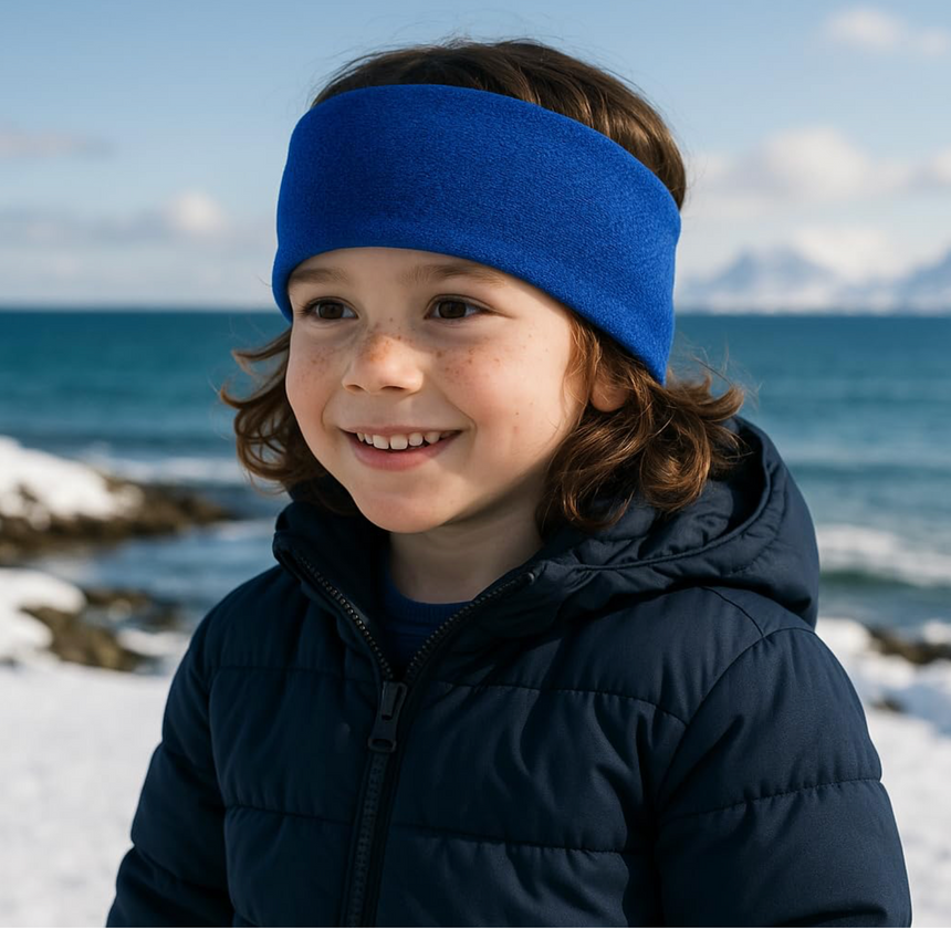 Kind am verschneiten Strand trägt Wollhuhn Elastisches Öko Stirnband SPORTFLEECE, hält Ohren warm. Ideal für kalte Tage, handgefertigt in Deutschland.
