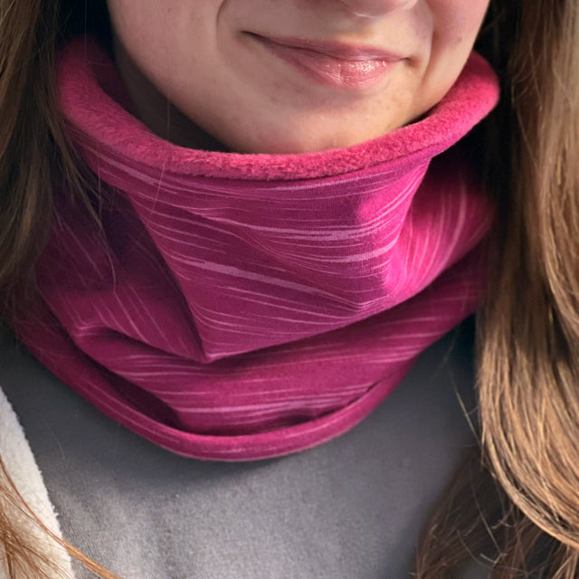 Frau trägt Wollhuhn Halstuch / Schlupfschal / Loop WARM mit Fleece-Innenfutter in Beere/Pink, ideal für kalte Tage und komfortables Tragen.