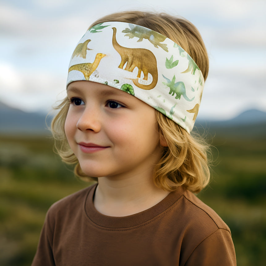 Kind mit Wollhuhn Elastisches Öko Stirnband Jersey Zweilagig Breit Dinos Beige, handgemacht und vielseitig, ideal für Schule und Outdoor-Aktivitäten.