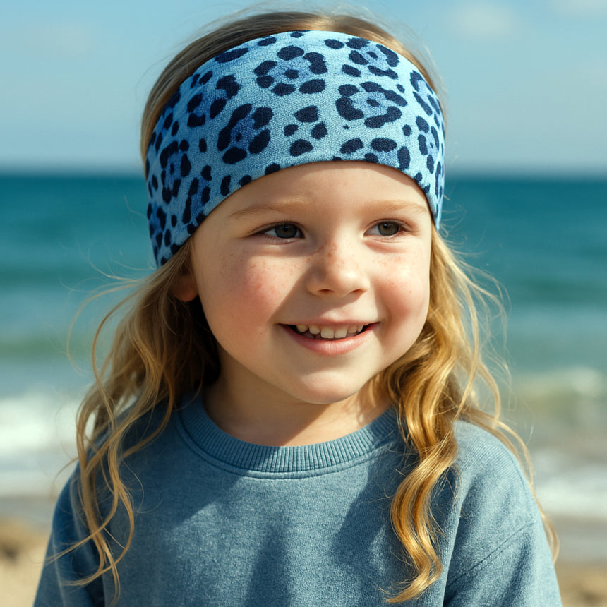 Nahaufnahme eines Kindes mit Wollhuhn Elastisches Öko Stirnband / Haarband Jersey Zweilagig Breit Leo Mini. Handgemacht, weich, vielseitig und ideal für Outdoor-Aktivitäten.