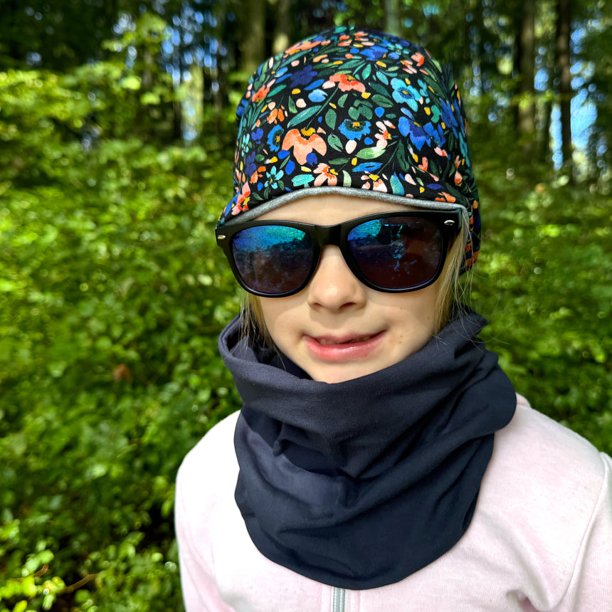 Mädchen trägt Wollhuhn Öko Long Beanie, zweilagig, mit floralem Design. Stilvoll und bequem, ideal für Kinder, hält Ohren warm.