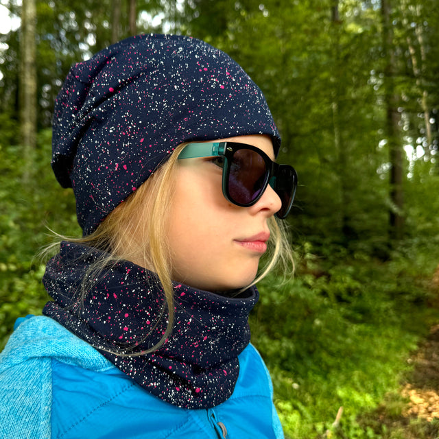 Frau im Wald trägt den Wollhuhn LONG Loop, Jersey- oder Fleecefutter, Galaxy Rot, als stilvollen, handgemachten Schal für Komfort und Schutz.