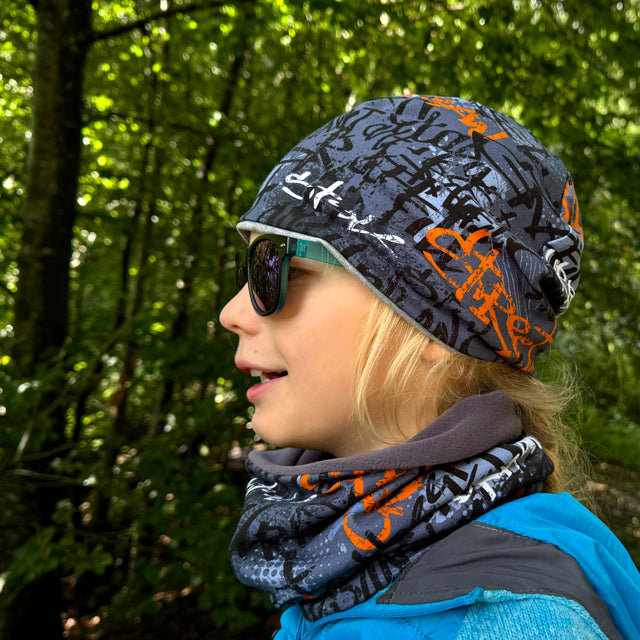 Wollhuhn LONG Loop, getragen von einem Mädchen mit Sonnenbrille, bietet Komfort und Schutz. Perfekt für Outdoor-Aktivitäten und handgefertigt in Deutschland.