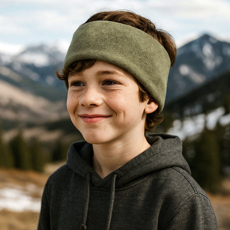 Junger Junge in den Bergen trägt Wollhuhn Elastisches Öko Stirnband, Fleece zweilagig, ideal bei kaltem Wetter. Perfekt für Kinder und Erwachsene, handgefertigt in Deutschland.