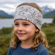 Mädchen trägt Wollhuhn Elastisches Öko Stirnband/Haarband, Jersey, zweilagig, breit, ideal für vielseitige Outdoor-Aktivitäten. Handgemacht in Deutschland, weich und dehnbar.
