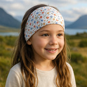Wollhuhn Elastisches Öko Stirnband, zweilagig, zeigt ein Mädchen mit geblümtem Stirnband, das handgefertigt aus Bio-Jersey ist, ideal für Kinder und Erwachsene.