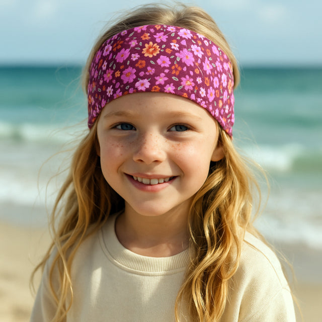 Mädchen lächelt in die Kamera und trägt das Wollhuhn Elastisches Öko Stirnband Jersey Zweilagig Breit Blumen Beere, ideal für Schule und Freizeit.