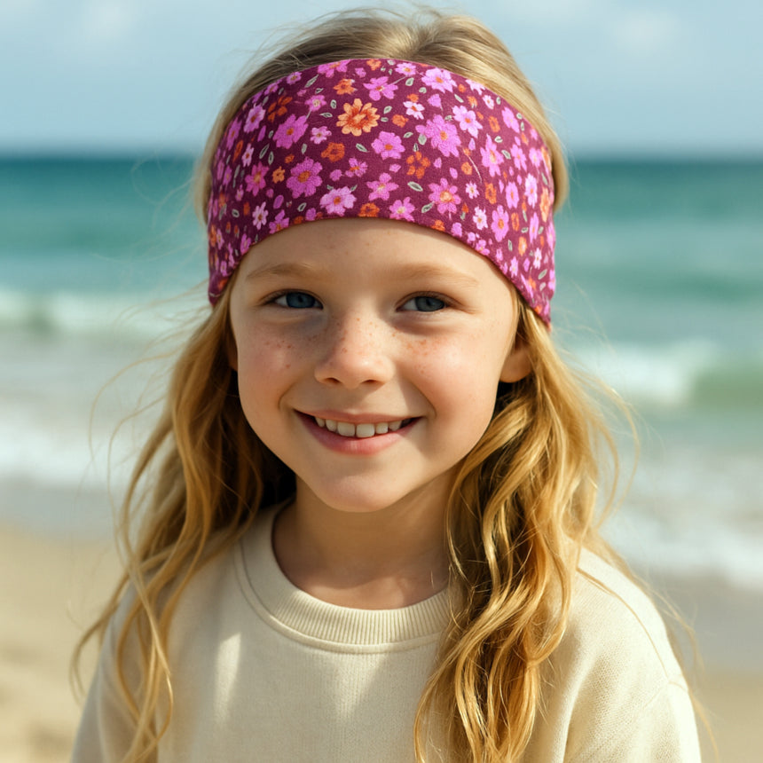Mädchen lächelt in die Kamera und trägt das Wollhuhn Elastisches Öko Stirnband Jersey Zweilagig Breit Blumen Beere, ideal für Schule und Freizeit.