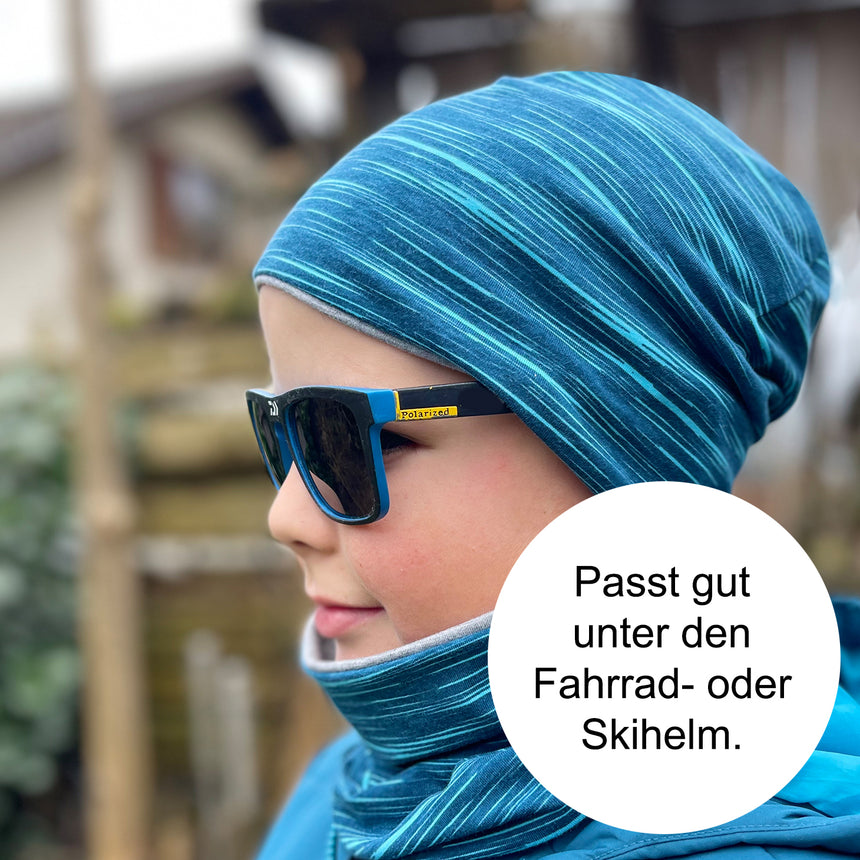 Kind trägt Wollhuhn Öko Shorties, eine handgemachte, zweilagige Wendemütze. Perfekt für aktive Kinder, bequem und stilvoll mit wärmenden Eigenschaften.