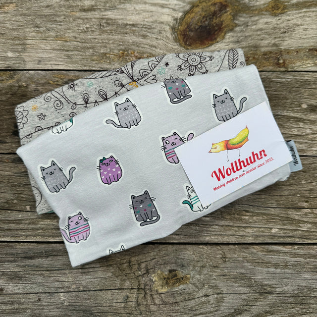 Beanie Überraschungstüte mit gefalteten Decken und Katzendruck auf Holzoberfläche, repräsentativ für Wollhuhns handgefertigte, hochwertige Mützenangebote.