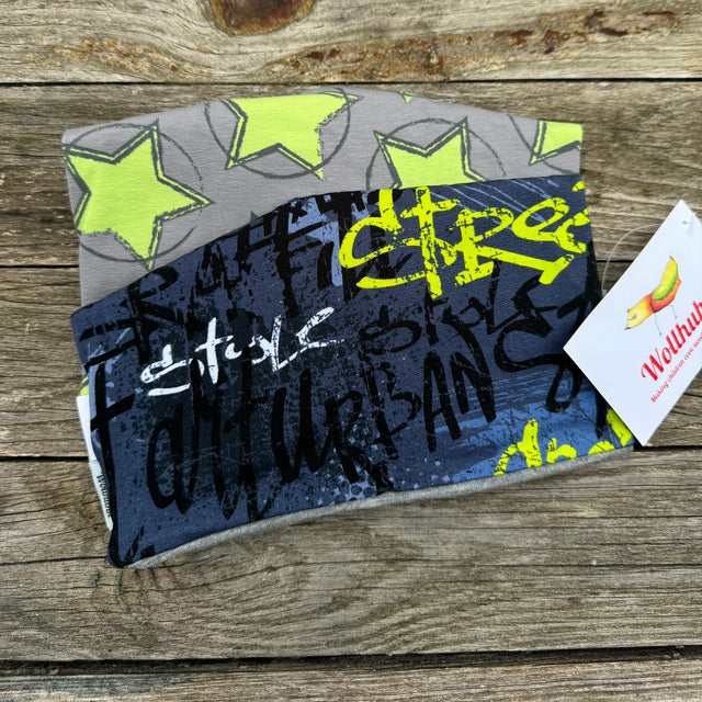 Beanie Überraschungstüte mit handgemachten Mützen, darunter Stoffe mit gelben Sternen und Graffiti-Motiv. Hochwertige, regional produzierte Accessoires für Kinder.