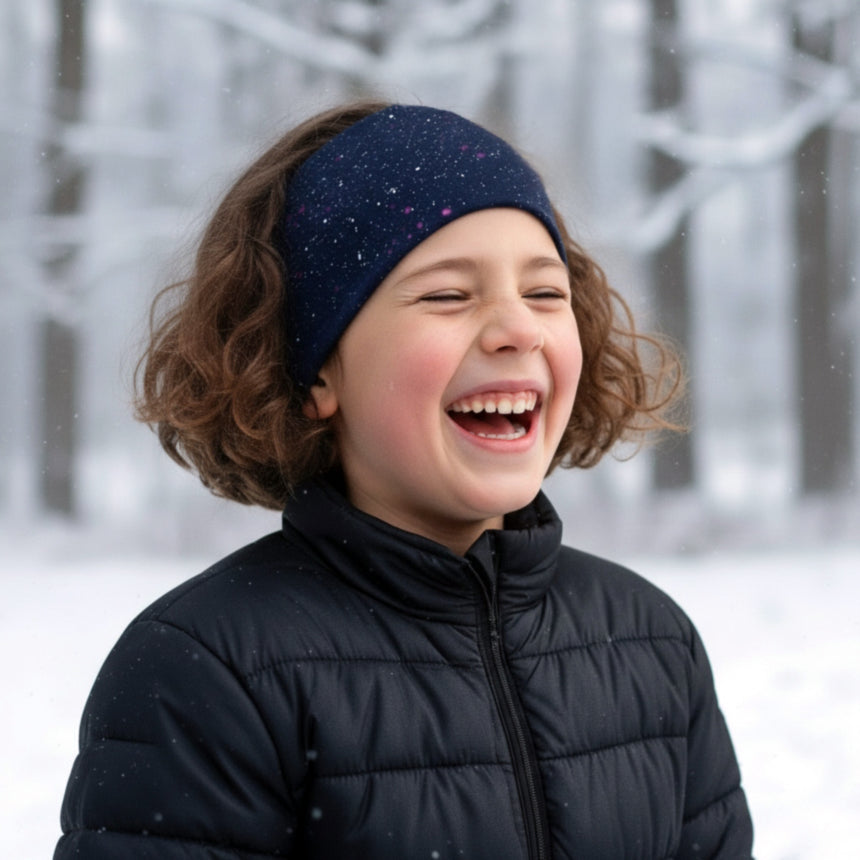 Kind lacht im Schnee, trägt ein Wollhuhn Elastisches Öko Stirnband / Haarband Jersey Zweilagig Breit Galaxy Sprenkel Rot, ideal für kaltes Wetter und sportliche Aktivitäten.