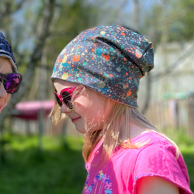 Zwei Mädchen tragen die Wollhuhn Öko Long Beanie Wendemütze, ideal für alle Jahreszeiten, aus weichem Baumwolljersey, für Komfort und Wärme.