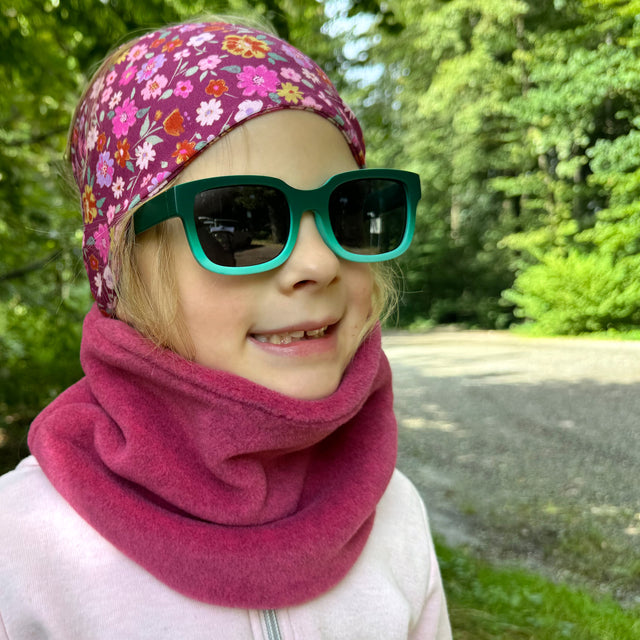 Mädchen trägt Wollhuhn WINTER Halstuch „Unser Wärmster“, doppellagiger Fleece-Schal, ideal für kalte Tage, handgefertigt in Deutschland, mit Sonnenbrille und Kopftuch.