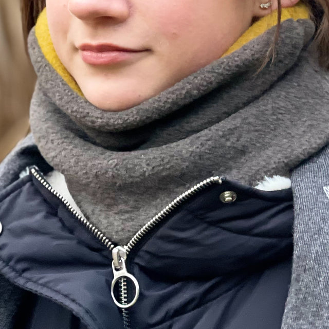 Frau trägt Wollhuhn WINTER Halstuch „Unser Wärmster“, ein doppellagiger, handgemachter Fleece-Schlupfschal in Schwarz, ideal für Kälte- und Windschutz.