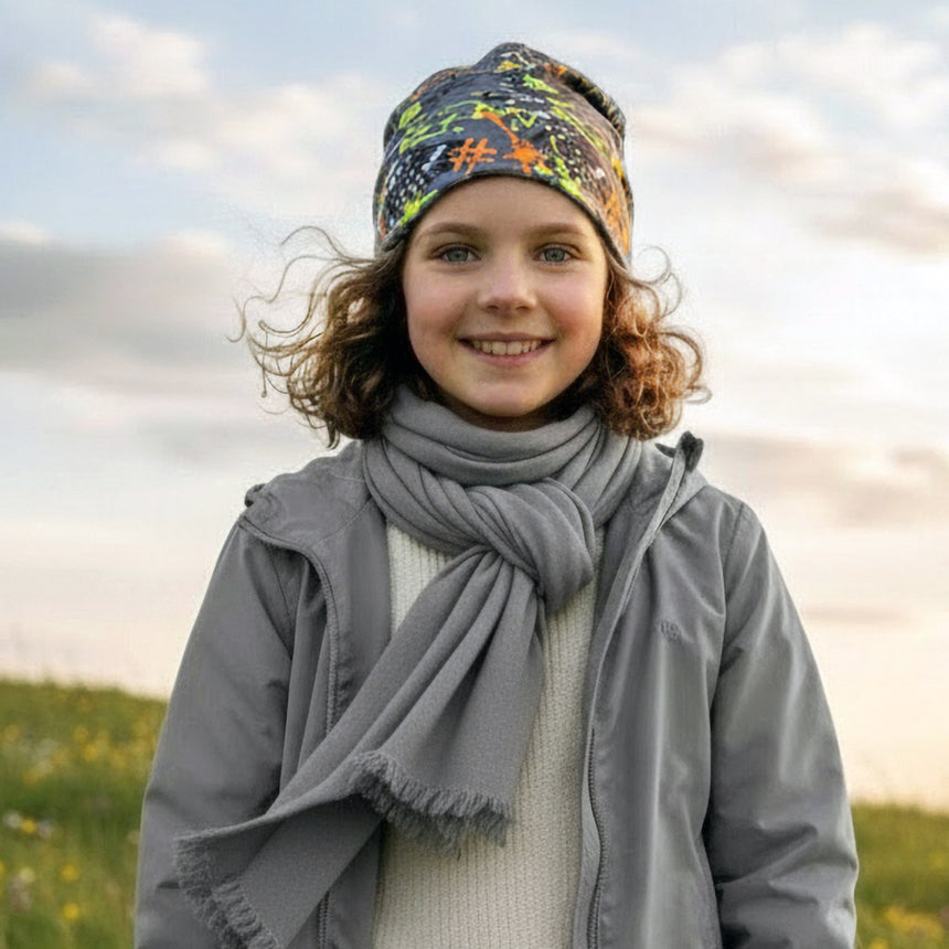 Kind im Freien trägt Wollhuhn Öko Long Beanie, zweilagig, graffiti grau/bunt, ideal für Frühling und Herbst, lässiger Look, handgemacht in Deutschland.