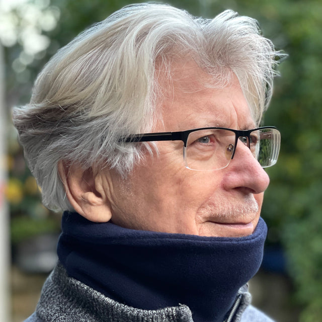 Mann mit Brille trägt Wollhuhn WINTER Halstuch/Schlupfschal „Unser Wärmster“, doppellagiger Fleece, einfarbig Dunkelblau, handgefertigt für Wärme und Komfort.