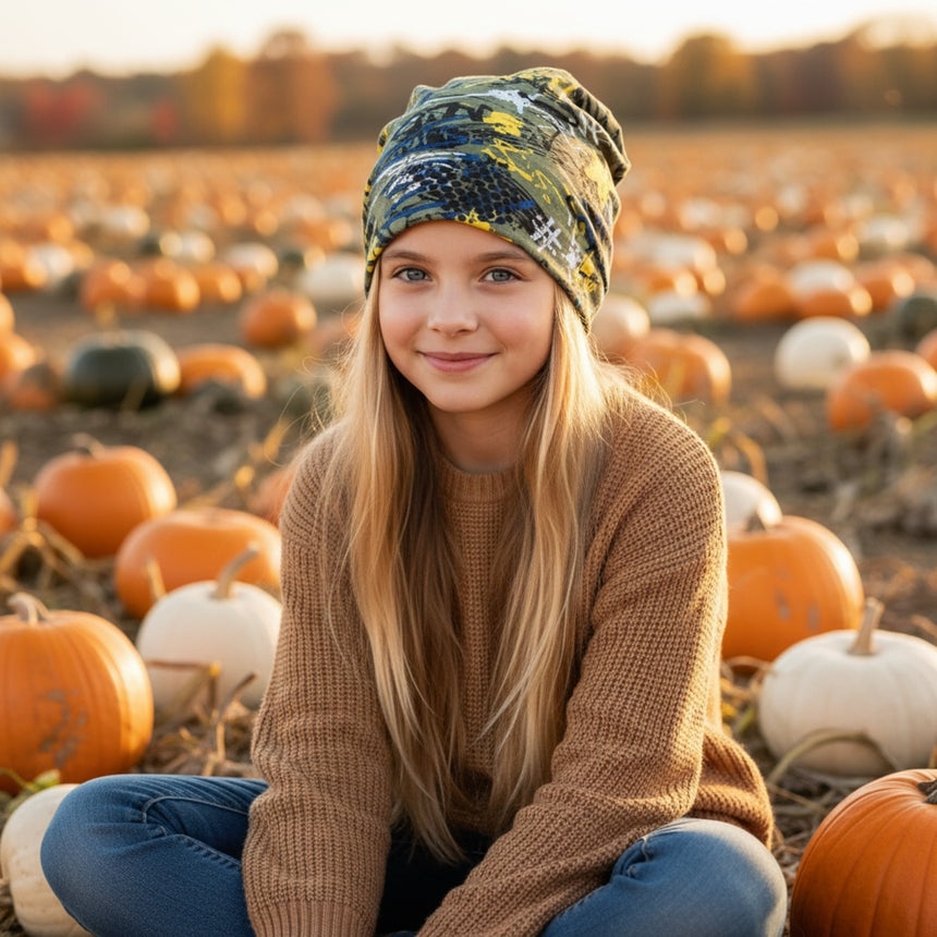 Mädchen im Kürbisfeld trägt Wollhuhn Öko Long Beanie, zweilagig und wendbar, ideal für Herbst. Handgemacht, lässiger Sitz, perfekte Wahl für Kinder.