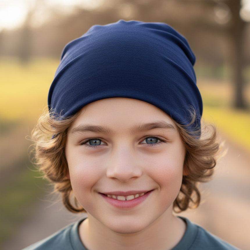 Porträt eines Kindes mit Wollhuhn Öko Shorties: Dunkelblaue, zweilagige Beanie-Mütze aus Öko-Jersey. Handgefertigt, bequem und ideal für aktive Kinder.
