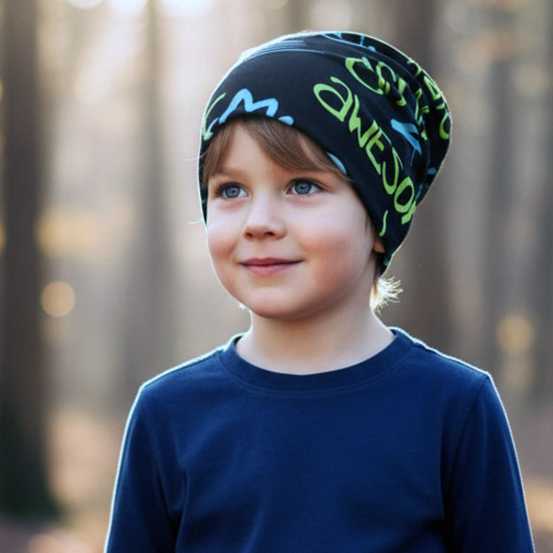 Ein Vorschuljunge trägt die Wollhuhn Öko Wendemütze, Ganzjährig, Zweilagig, Cool Music Schwarz, eine bequeme Longbeanie aus weichem Baumwolljersey, ideal für Kinder.