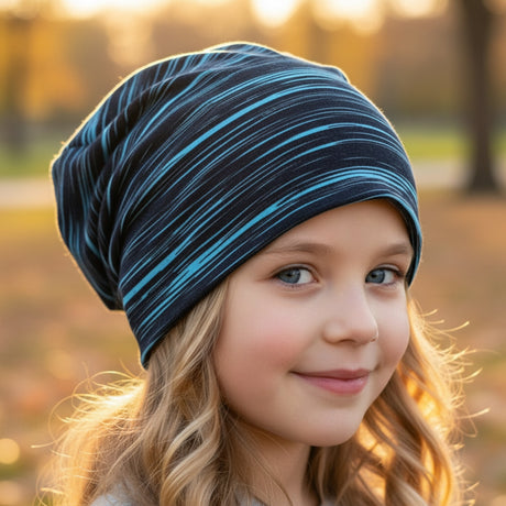 Mädchen im Park mit Wollhuhn Öko Long Beanie, zweilagig, schwarz/türkis gestreift, lässiger Sitz. Ideal für Herbst, handgefertigt in Deutschland.