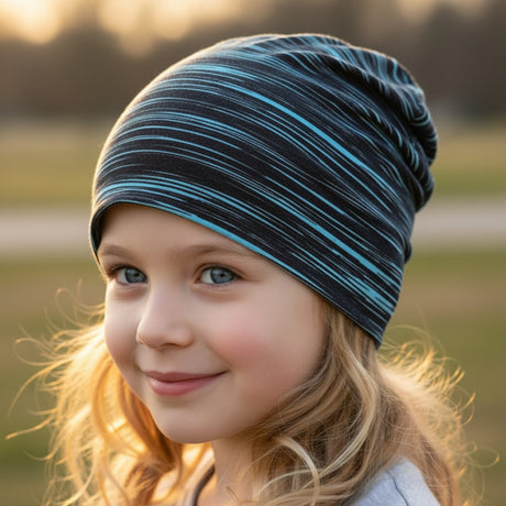 Kind trägt eine Wollhuhn Öko Shorties Wendemütze, zweilagig, Ganzjährig nutzbar, in Lines Schwarz/Türkis. Sie lächelt im Freien, warm eingepackt.