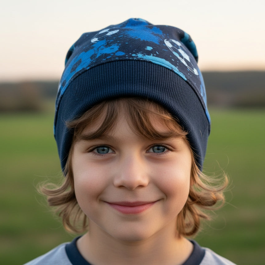 Junge trägt Wollhuhn Dünne Öko Beanie-Mütze Sommer/Übergang Einlagig in Blautönen, ideal für aktive Kinder, handgemacht und bequem, passend für sportliche Aktivitäten.