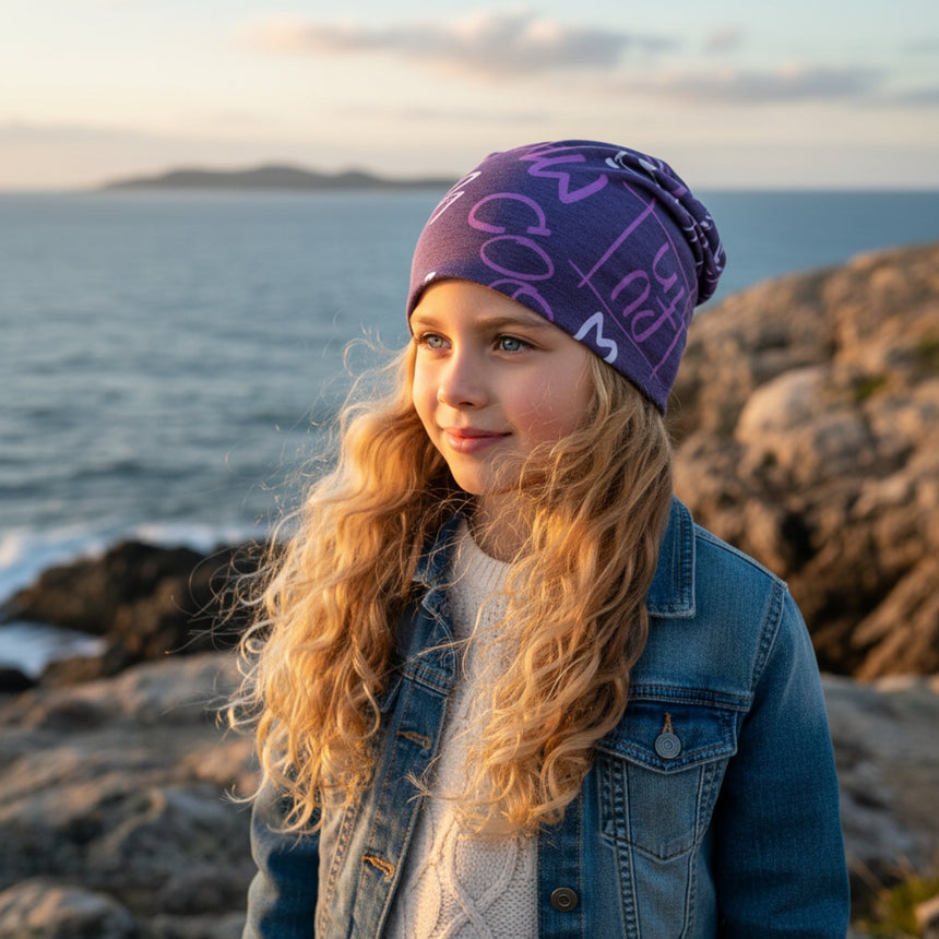 Mädchen am Meer mit Wollhuhn Öko Long Beanie, lila, zweilagig. Handgemacht, stilvoll und nachhaltig, ideal für Übergangszeiten. Perfekt für Kinder und Jugendliche.