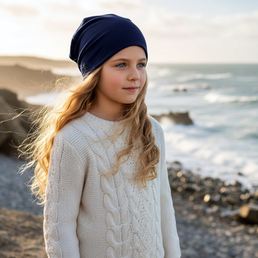 Mädchen am Meer in Wollhuhn Öko Long Beanie, dunkelblau, zweilagig. Handgemacht, lässiger Stil, perfekt für das ganze Jahr.