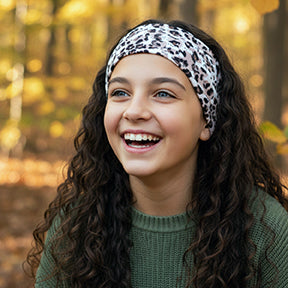 Mädchen mit Wollhuhn Elastisches Öko Stirnband / Haarband Jersey Zweilagig Breit Leo Creme, lächelt im herbstlichen Park, trägt grünen Pullover.