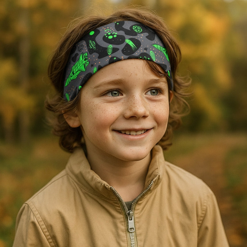 Ein Junge trägt ein Wollhuhn Elastisches Öko Stirnband Jersey Zweilagig Breit Space/Rakete Neon Grün, ideal für Outdoor-Aktivitäten, handgemacht und bequem.