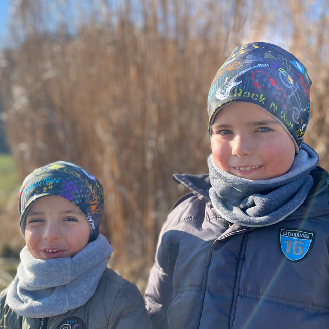 Zwei Kinder tragen Wollhuhn Öko Long Beanie Wendemützen, ideal für jede Jahreszeit und aus weichem Baumwolljersey gefertigt, perfekt für Komfort und Stil.