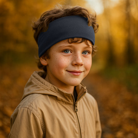 Junge mit Wollhuhn Elastisches Öko Stirnband, dunkelblau, auf einem herbstlichen Pfad. Handgemachtes, vielseitiges Stirnband, ideal für Outdoor-Aktivitäten.